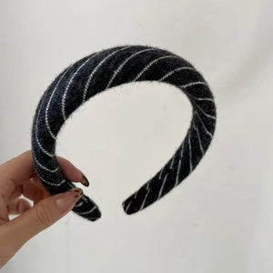Close-up of a padded black knitted headband with white diagonal stripe patterns