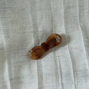 Detail view of amber marble acetate bow hair clip with sparkling rhinestone accents