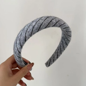 Close-up of a grey striped knitted headband showing the soft texture and thick design