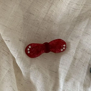 Detail view of a vintage red acetate bow hair clip with sparkling rhinestone accents