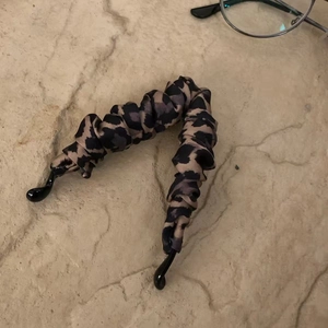 Pince à cheveux banane en satin à motif léopard sur fond de pierre texturée