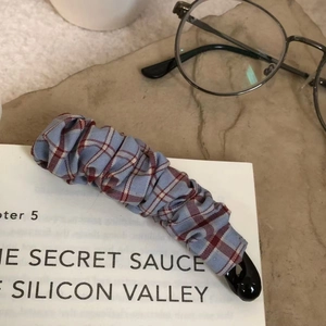 Barrette banane à carreaux rouges et bleus avec tissu plissé sur des livres anciens