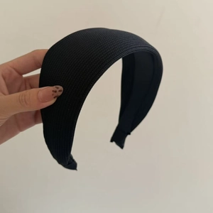 Close-up of thick black knitted fabric headband showing detailed ribbed texture and soft padding