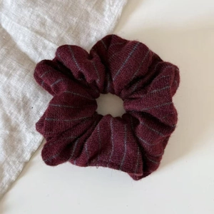 Macro shot of striped burgundy knit scrunchie with soft grey linear patterns
