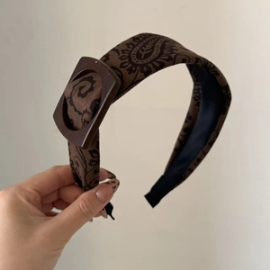 Detail of coffee brown paisley headband with decorative square buckle and soft velvet texture