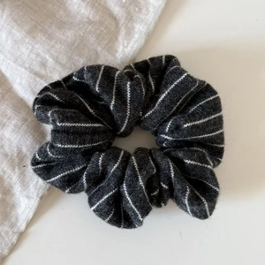 Close-up of thick knitted striped scrunchie with soft grey and black wool texture