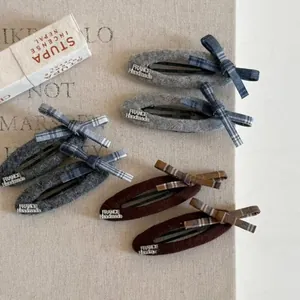Detail of plaid wool bow hair clips with France Handmade label on fabric base