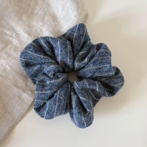 Close-up of a striped knit scrunchie with navy blue and white patterns on fabric