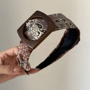 Close-up of retro paisley print wide headband with large square dark brown decorative buckle