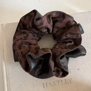 Detailed view of large leopard print and dark brown faux leather patchwork scrunchie