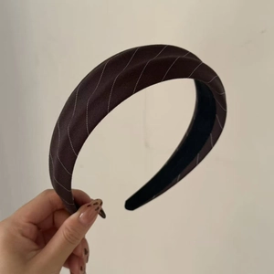 Detail shot of brown fabric headband with white diagonal stripes and wide vintage design