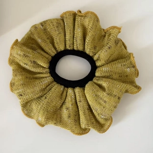 Detailed macro view of ginger yellow knitted hair scrunchie with mixed fiber texture