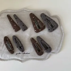 Detailed knit texture and polka dot pattern on grey and brown wool fabric BB hair clips