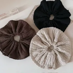 Detailed texture of brown, black, and beige knitted scrunchies in a flat lay display