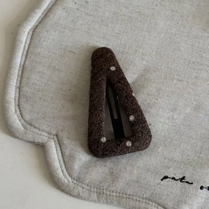 Detailed view of dark brown wool fabric BB clip with white polka dots on linen fabric