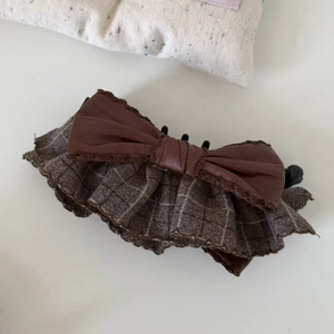 Detail of a brown layered bow hair clip with vintage plaid ruffles and leather texture