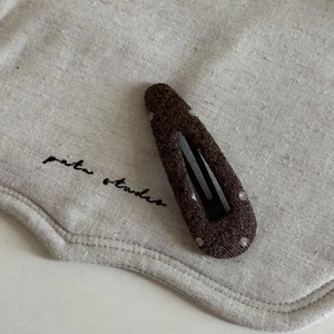 Macro shot of dark brown wool felt BB hair clip with white polka dots and stitched edges