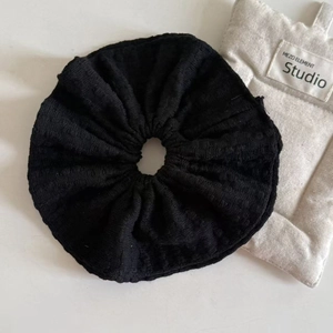 Detail shot of the black double-layered knit scrunchie texture and soft pleated fabric