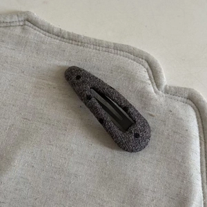 Detail of charcoal grey wool fabric BB clip with polka dot texture and metal snap
