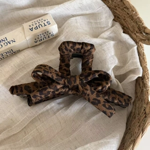 Close-up of leopard print bow hair claw clip on linen cloth with a natural aesthetic