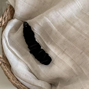 Close-up of elegant black velvet banana hair clip with pleated fabric texture and lock
