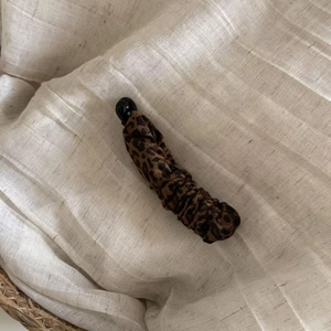 Detail view of leopard print velvet banana hair clip with a black bead on soft linen fabric