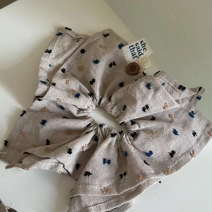 Oatmeal linen scrunchie with colorful dots and a decorative white tag and button