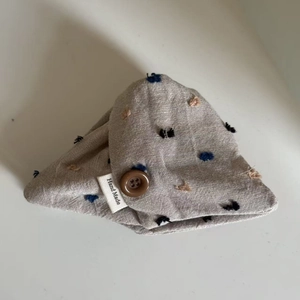 Detail of oatmeal cotton linen hair tie with embroidered dots and vintage button closure