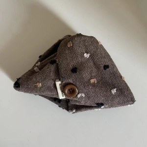 Close-up of oatmeal fabric hair accessory with colorful polka dots and handmade label