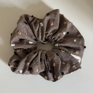Close-up of oatmeal fabric scrunchie with button accents and woven texture detail