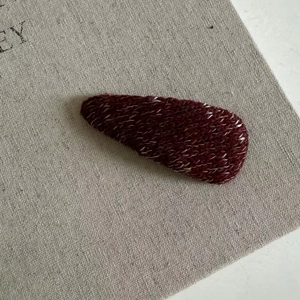 Macro shot of mixed burgundy wool knit water-drop hair clip texture and winter craft
