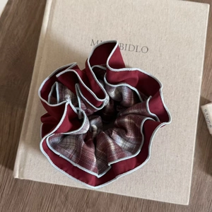 Detailed close-up of blue and red plaid hair scrunchie showing fine fabric texture and piping