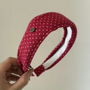 Close-up of red polka dot knit headband featuring a small silver heart-shaped charm detail