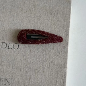 Macro shot of red tweed texture on teardrop snap clip over beige burlap background