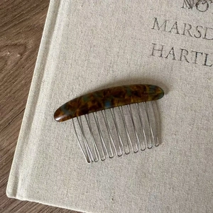 Macro detail of tortoiseshell acetate hair comb with 12 silver metal teeth on linen cloth