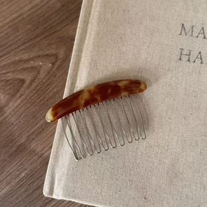 Detail of tortoise shell acetate hair comb with silver metal teeth and handmade engraving
