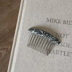 Close-up of acetic acid hair comb with black and white marble pattern on book