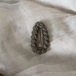 Detailed macro view of a handmade crochet hair clip in olive green with a metal BB fastener