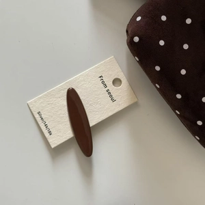 Close-up of a glossy brown oval hair claw clip displayed on a branded white card