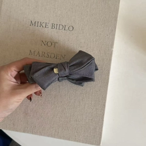 Elegant dark grey fabric bow hair clip with central gold metal buckle accessory