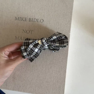 Close-up of vintage plaid bow hair clip with luxury gold logo plate detail