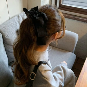Elegant large black oversized bow hair clip for ponytail styles on casual indoor model