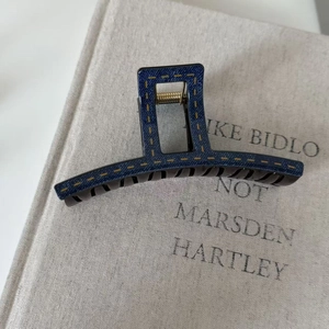 Close-up of a blue denim texture hair claw clip with yellow contrast stitching details
