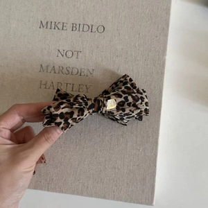 Detail of leopard print bow hair clip with golden metal buckle and textured fabric