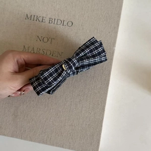 Detailed close-up of a black and white plaid bow hair clip featuring a vintage gold center buckle