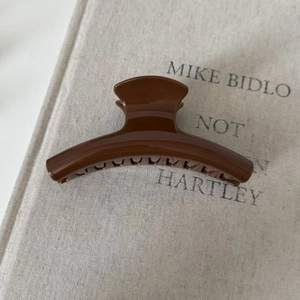 Macro view of a glossy dark brown hair claw clip on a linen textured background