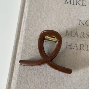 Detail of caramel brown hair claw clip with strong golden metal spring on burlap