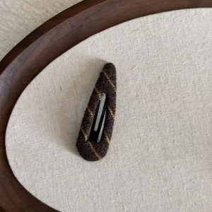 Detailed macro view showing the knitted texture and yellow stripes on the brown BB hair clip