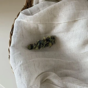 Detail of a handmade plush caterpillar hair clip in green and grey knitted wool