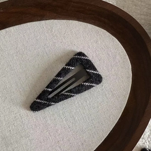 Close-up of a triangle BB clip featuring black and white striped knitted wool texture